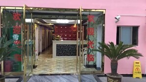 A hotel entrance with a glass door, a reception desk, and a potted plant. - Yueyi Hotel (Shanghai)