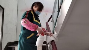 A person cleaning a window with a spray bottle and cloth. - Yueyi Hotel (Shanghai)