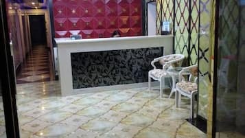 Uma área de recepção com parede estampada, balcão de recepção e área de estar com cadeiras.
