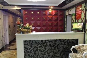 A hotel reception area with a reception desk, a decorative wall, and a digital screen displaying information. - Yueyi Hotel (Shanghai)