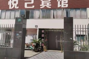 A hotel entrance with a sign above the doors, a gate, and a small outdoor area with a potted plant. - Yueyi Hotel (Shanghai)