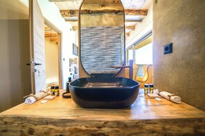 A bathroom with a large mirror, a black basin, and various toiletries on the counter. - Casa Astra (Hersonissos)