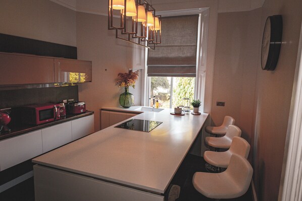 A modern kitchen with a central island, built-in appliances, and a window with a view.