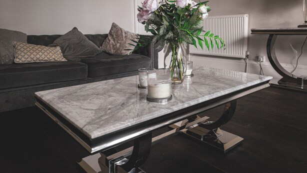 A modern living room with a marble coffee table, a vase with flowers, and a grey sofa with cushions. - Beautiful Apartment in Stirling (Stirling)