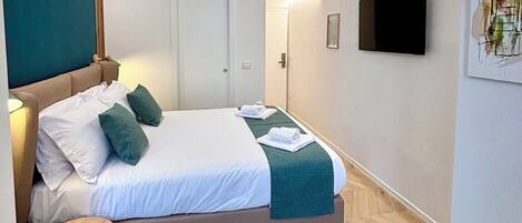 Una habitación de hotel moderna con una cama, una mesita de noche y un televisor de pantalla plana en la pared.