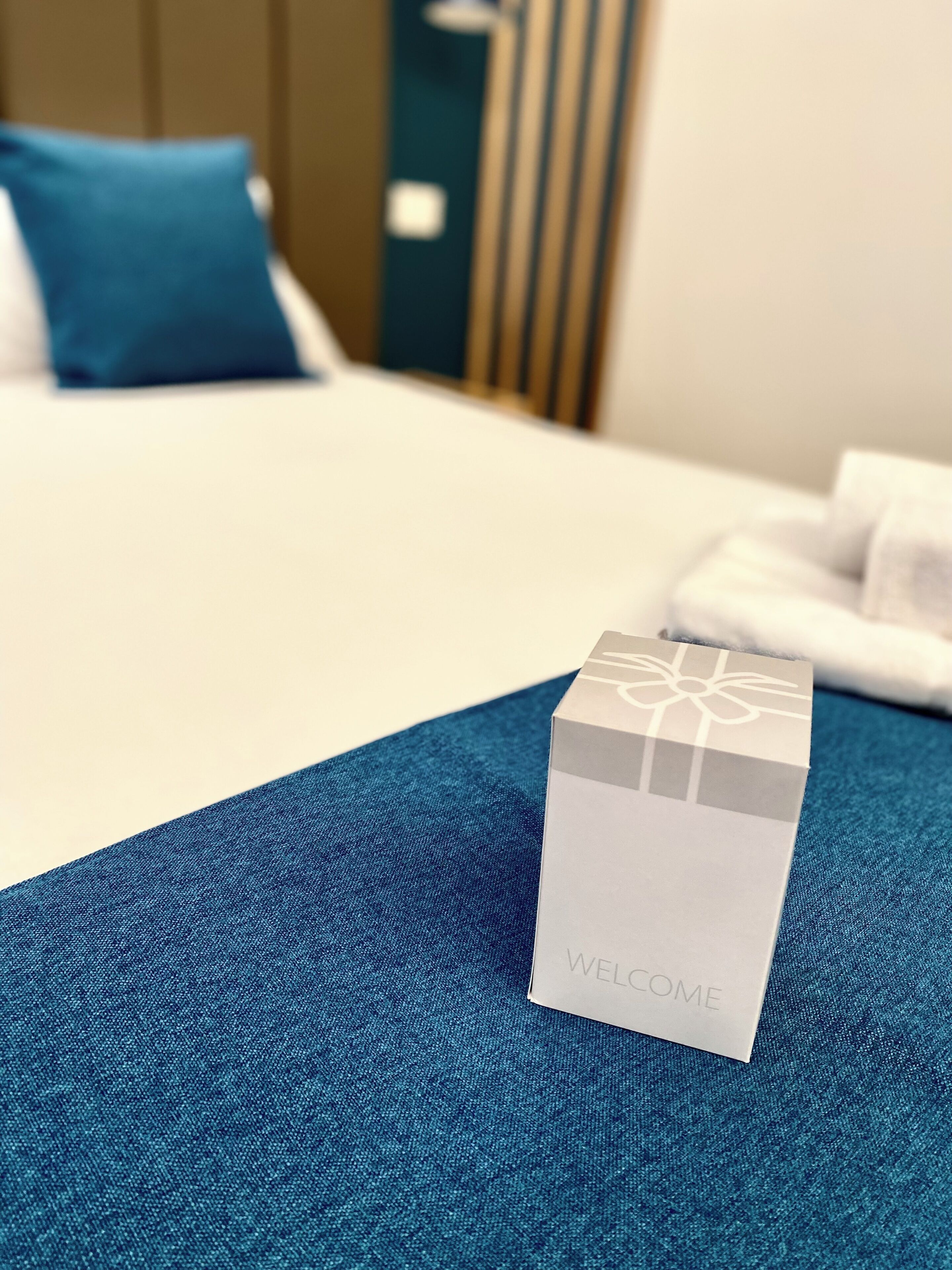 Une boîte de bienvenue posée sur un lit recouvert d’une couverture bleue.