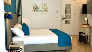 A modern bedroom with a bed, a wall-mounted air conditioner, a painting, and a small table with a lamp.