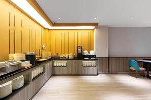 Una cocina moderna con una encimera amplia, electrodomésticos integrados y una zona de estar con una silla.