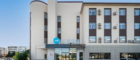 Un hotel moderno con fachada plana, varias unidades de aire acondicionado y un cielo despejado.