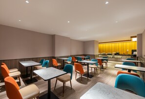 A modern dining area with tables and chairs, a counter with a yellow accent wall, and a seating area with a view. - Hanting Hotel Beijing Beiqijia Future Technology C (Beijing)