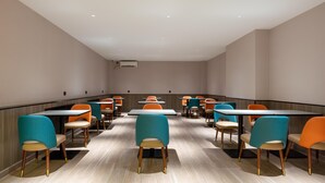 Ein moderner Essbereich mit Tischen und Stühlen, Holzboden und abgehängter Decke.