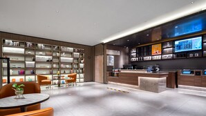A modern hotel lobby with a reception desk, seating area, and a bookshelf filled with books. - Hanting Hotel Beijing Beiqijia Future Technology C (Beijing)