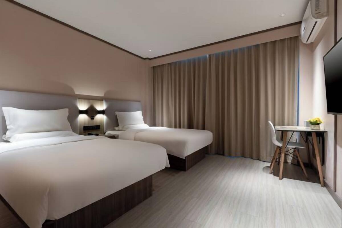 Een hotelkamer met twee bedden, een bureau en een televisie.