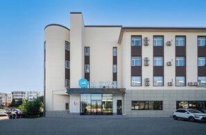 Ein modernes Gebäude mit einem Schild, auf dem '汉庭酒店' (Han Tian Hotel) steht. Es hat eine geschwungene Fassade, zahlreiche Fenster und Klimaanlagen.