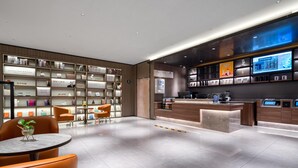 Eine moderne Hotelhalle mit Empfangstresen, einer Lounge und einem Bücherregal voller Bücher.