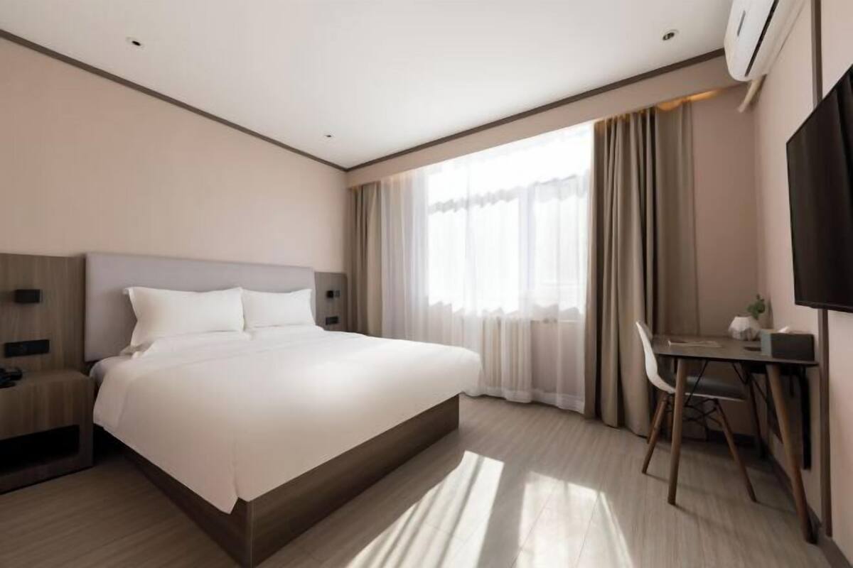 Een moderne hotelkamer met een groot bed, een bureau en een televisie.