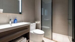 A modern bathroom with a glass shower enclosure, a white toilet, and a wooden vanity with a mirror. - Hanting Hotel Beijing Beiqijia Future Technology C (Beijing)