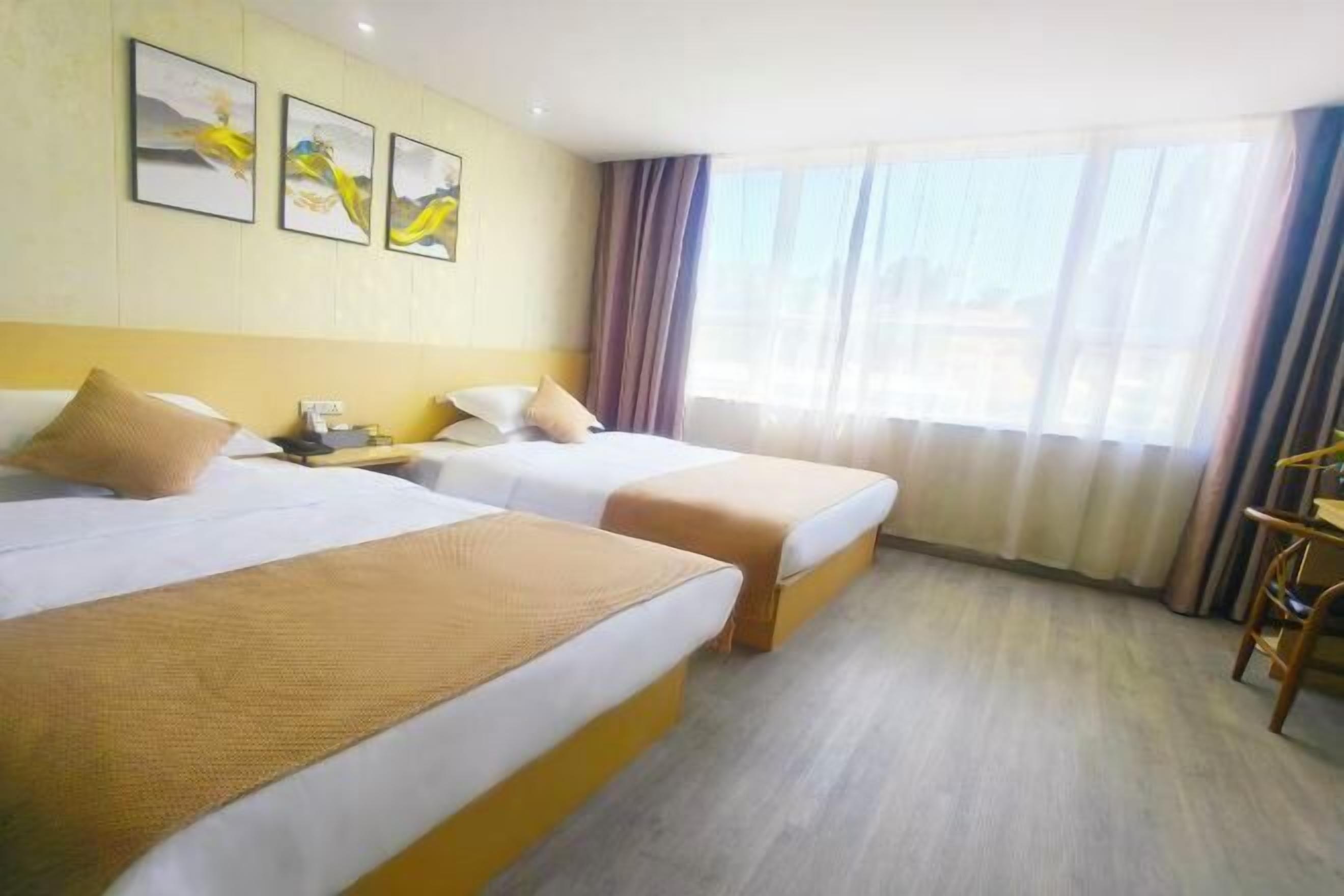 Une chambre d’hôtel avec deux lits, un bureau et une fenêtre avec des rideaux.