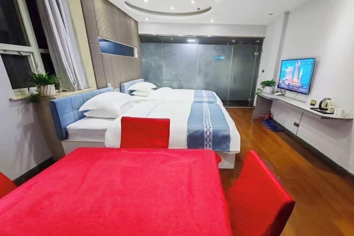 Une chambre d’hôtel moderne équipée d’un lit, d’une télévision, d’un bureau et d’une table rouge.