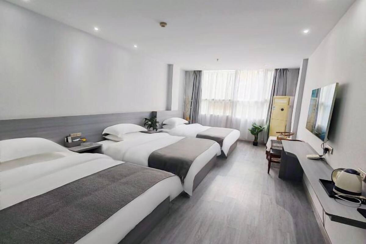 Une chambre d’hôtel avec deux lits, un bureau, une chaise, une télévision et une fenêtre avec des rideaux.