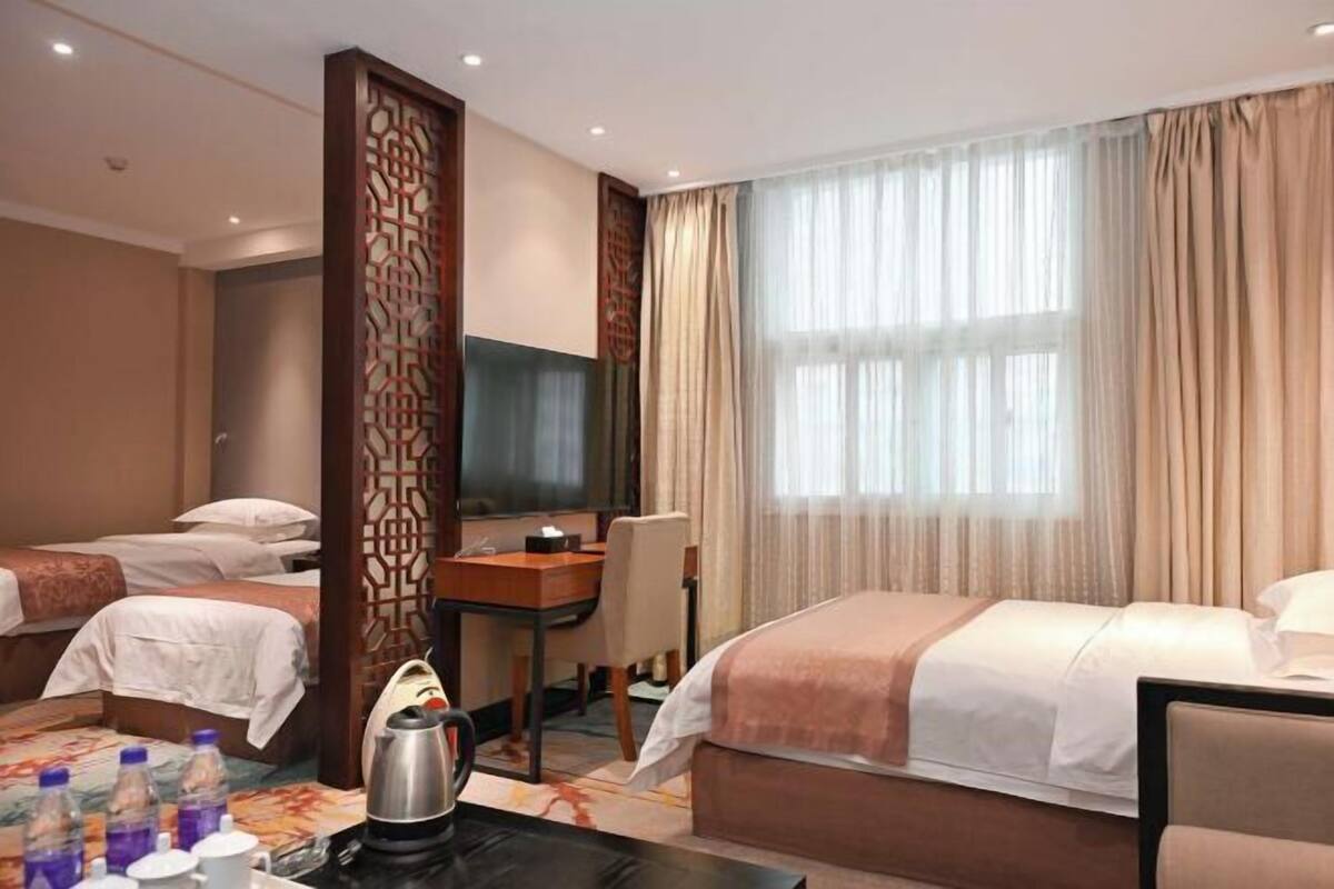 A hotel room with two beds, a desk, a TV, and a coffee maker.