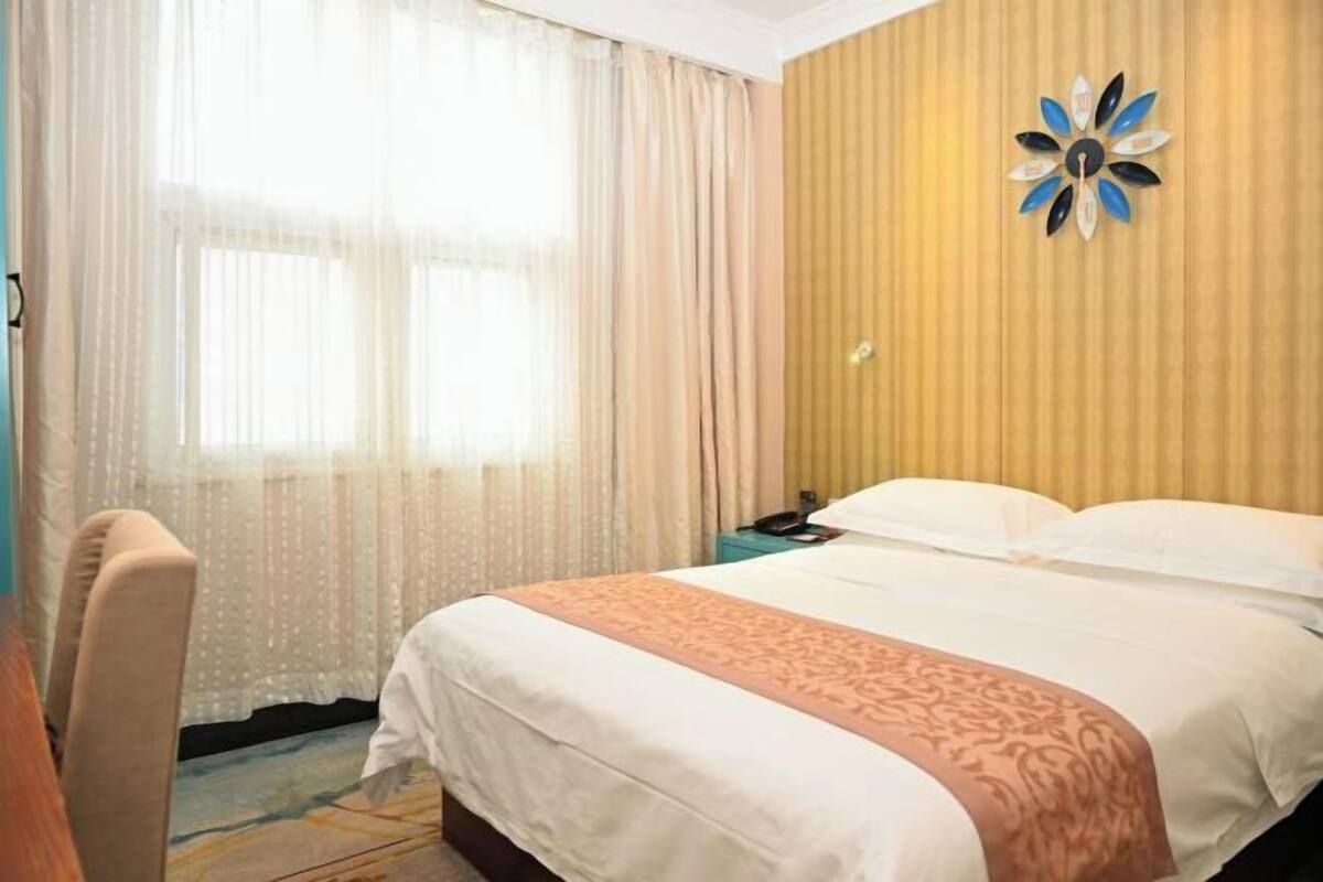 A hotel room with a bed, a chair, a nightstand, and a decorative wall piece.