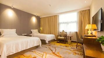 A hotel room with two beds, a desk, a chair, a TV, and a window with curtains.