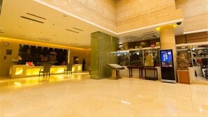 A spacious lobby with a reception desk, a digital information kiosk, and a large glass column. - Dongfang Yuehai Hotel (Zhengzhou)