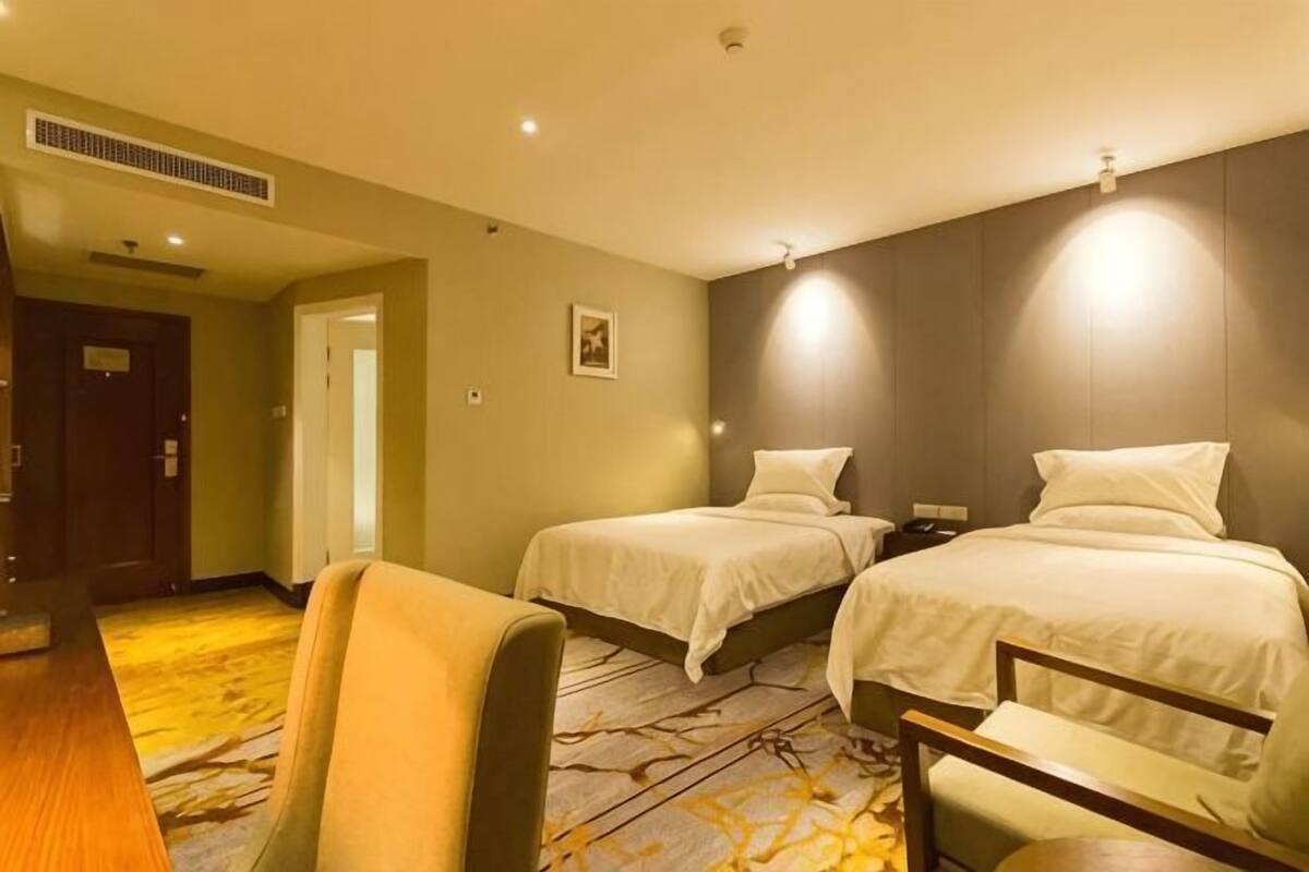 A hotel room with two beds, a desk, and a chair.