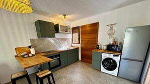 Eine kleine Küche mit Holztischplatte, einer Waschmaschine und einem Kühlschrank.
