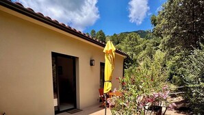 Eine Terrasse mit einem gelben Sonnenschirm, Gartenmöbeln und einem Gartenbereich mit Pflanzen und einer Holzterrasse.