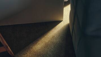 A carpeted floor with a shadow cast by a piece of furniture.