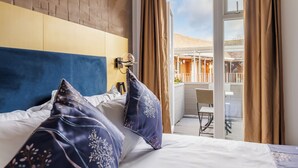 Una habitación de hotel con cama, cabecera, ventana con cortinas y vistas a un espacio exterior.