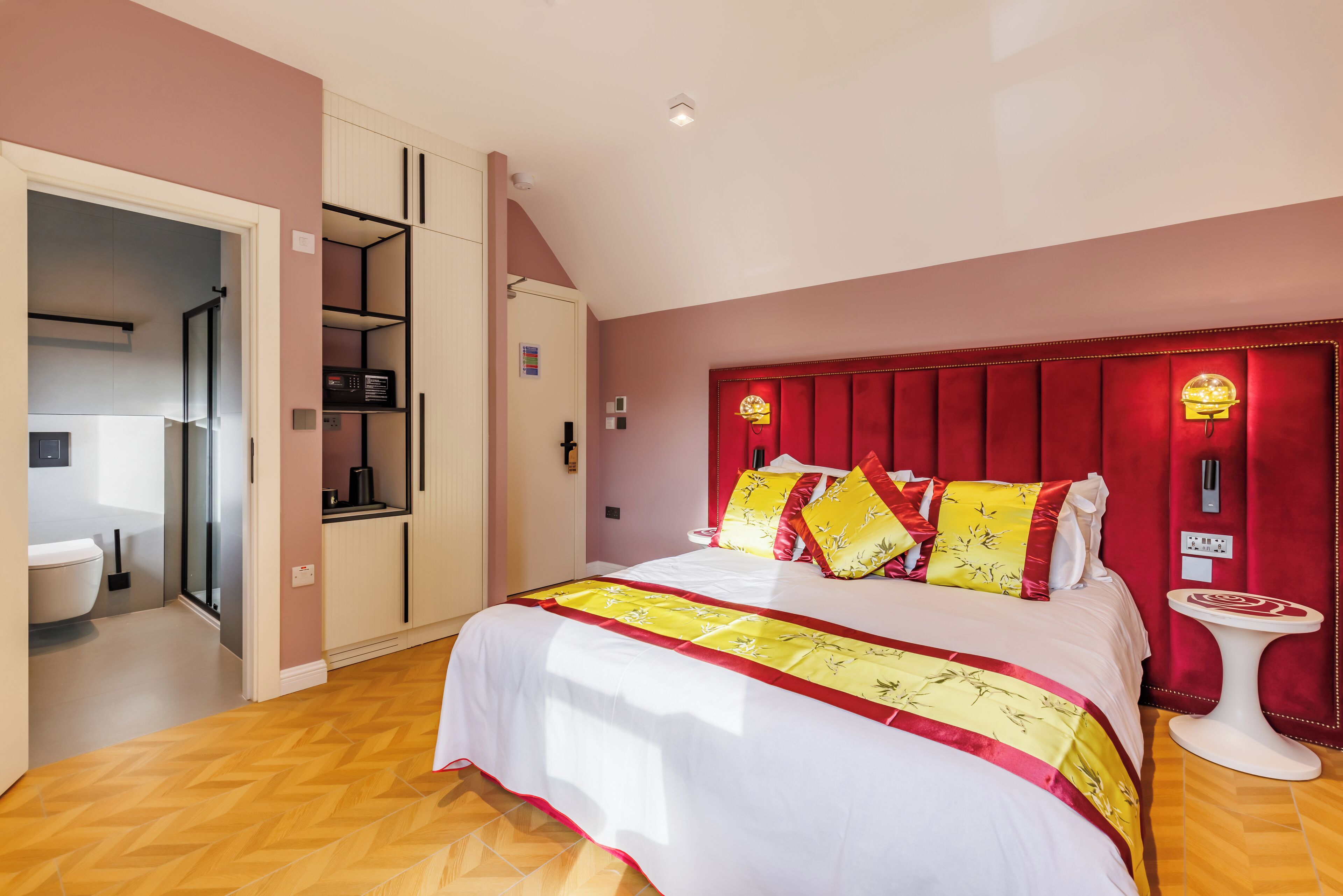 A bedroom with a bed, a red headboard, a bedside table, and a wardrobe.