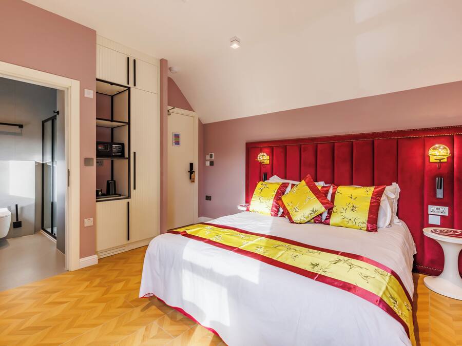 A bedroom with a bed, a red headboard, a bedside table, and a wardrobe.