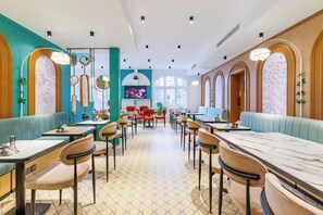 Un restaurant avec des banquettes et des tables, un écran de télévision et des miroirs décoratifs.