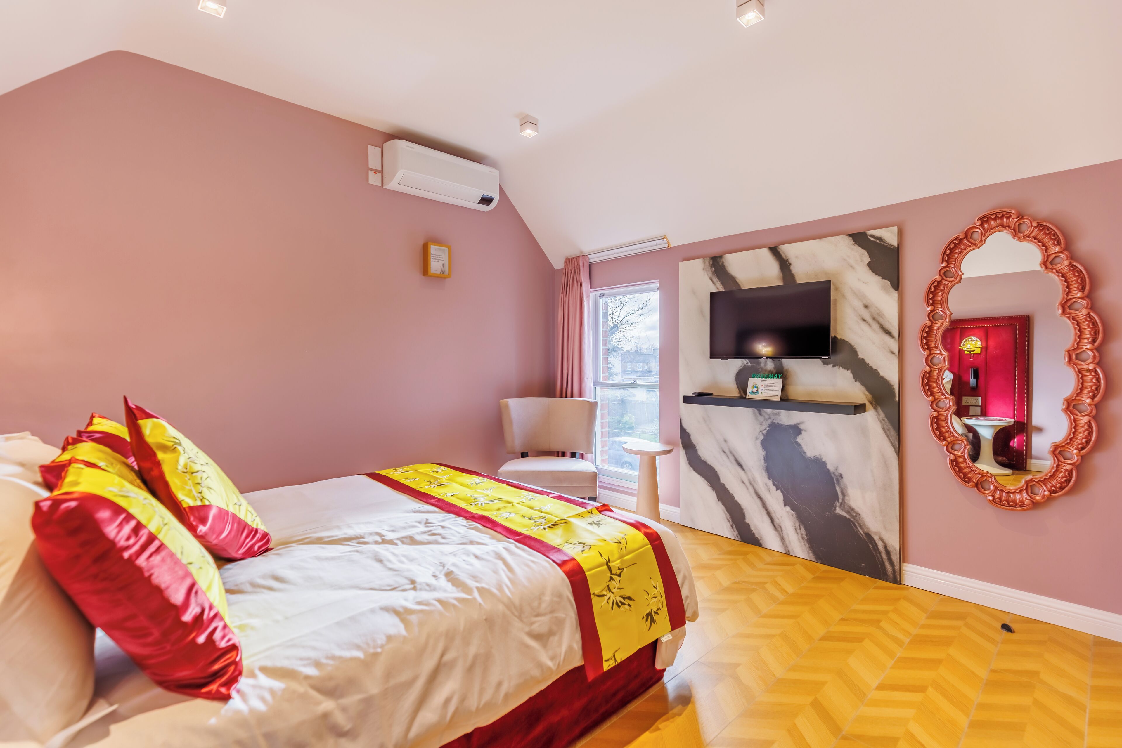 A bedroom with a bed, a TV, a mirror, and a window.