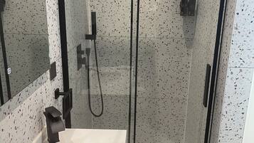 A modern bathroom with a glass-enclosed shower, a white sink, and a mirror.