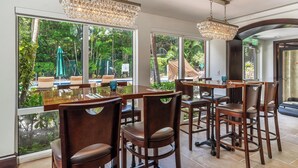 A dining area with large windows, wooden tables, and chairs.