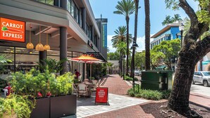 A commercial area with a 'CARROT EXPRESS' sign, outdoor seating, and a 'GOOD MORNING COCONUT GROVE' sign.