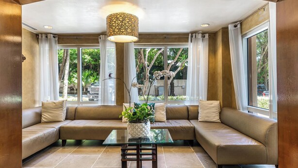 A modern living room with a beige sofa, a glass coffee table, and a potted plant.