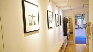 A hallway with framed artwork on the walls, a phone on the right, and a staircase leading to another room. - Superior Canary Wharf  O2 Arena 2Bed (London)
