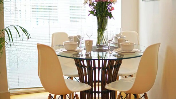 A dining table with chairs, a vase with flowers, and glassware. - Superior Canary Wharf  O2 Arena 2Bed (London)