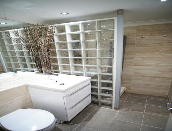A modern bathroom with a white vanity, a glass shower enclosure, and a tiled floor.