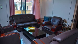 A modern living room with a sofa, two armchairs, a coffee table, and a small side table. - UNIQUE ROYAL HOTEL AND SUITES (Dodoma)