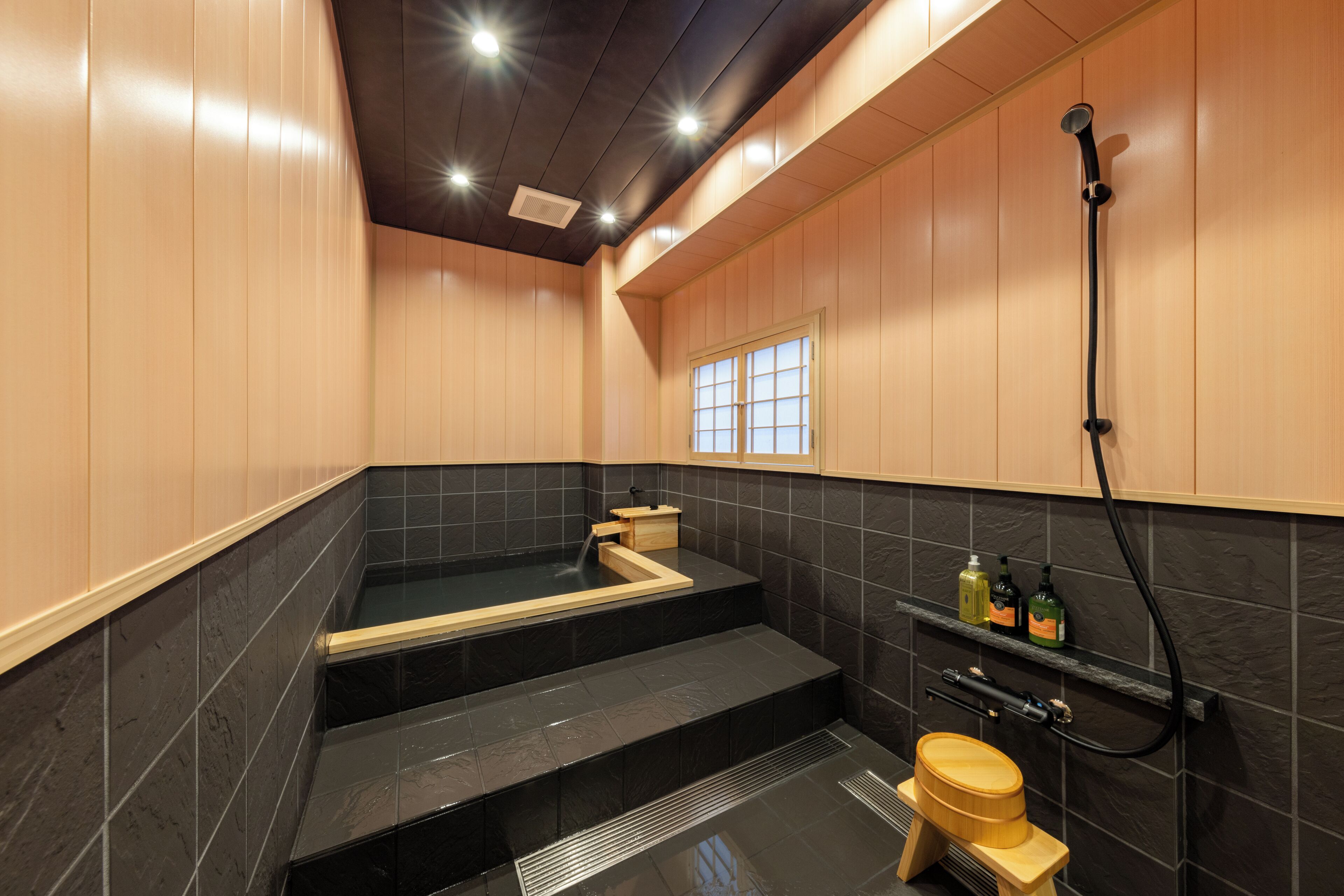 Une salle de bain moderne avec une baignoire noire, des toilettes en bois et une douche.