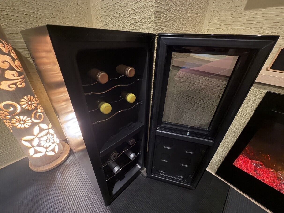 En hörna i ett rum med ett svart skåp som innehåller vinflaskor och en tv med svart ram.