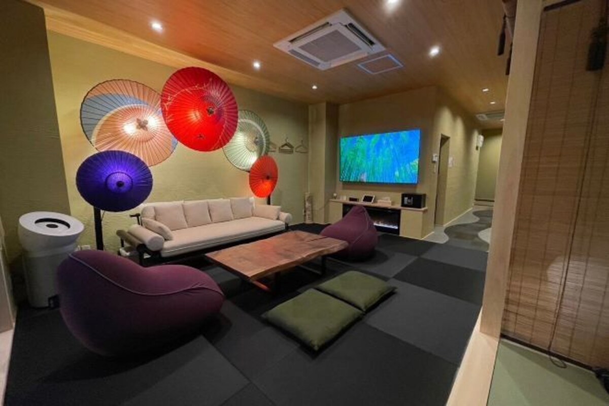 A modern living room with a sofa, two bean bags, a coffee table, and decorative umbrellas on the wall.