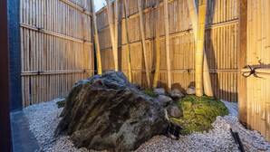 A traditional Japanese garden with bamboo fences, a large rock, and pebbles. - TAKENOYA (Osaka)