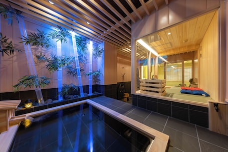 A traditional Japanese-style room with a tatami mat floor, a small indoor garden with bamboo, and a wooden ceiling.